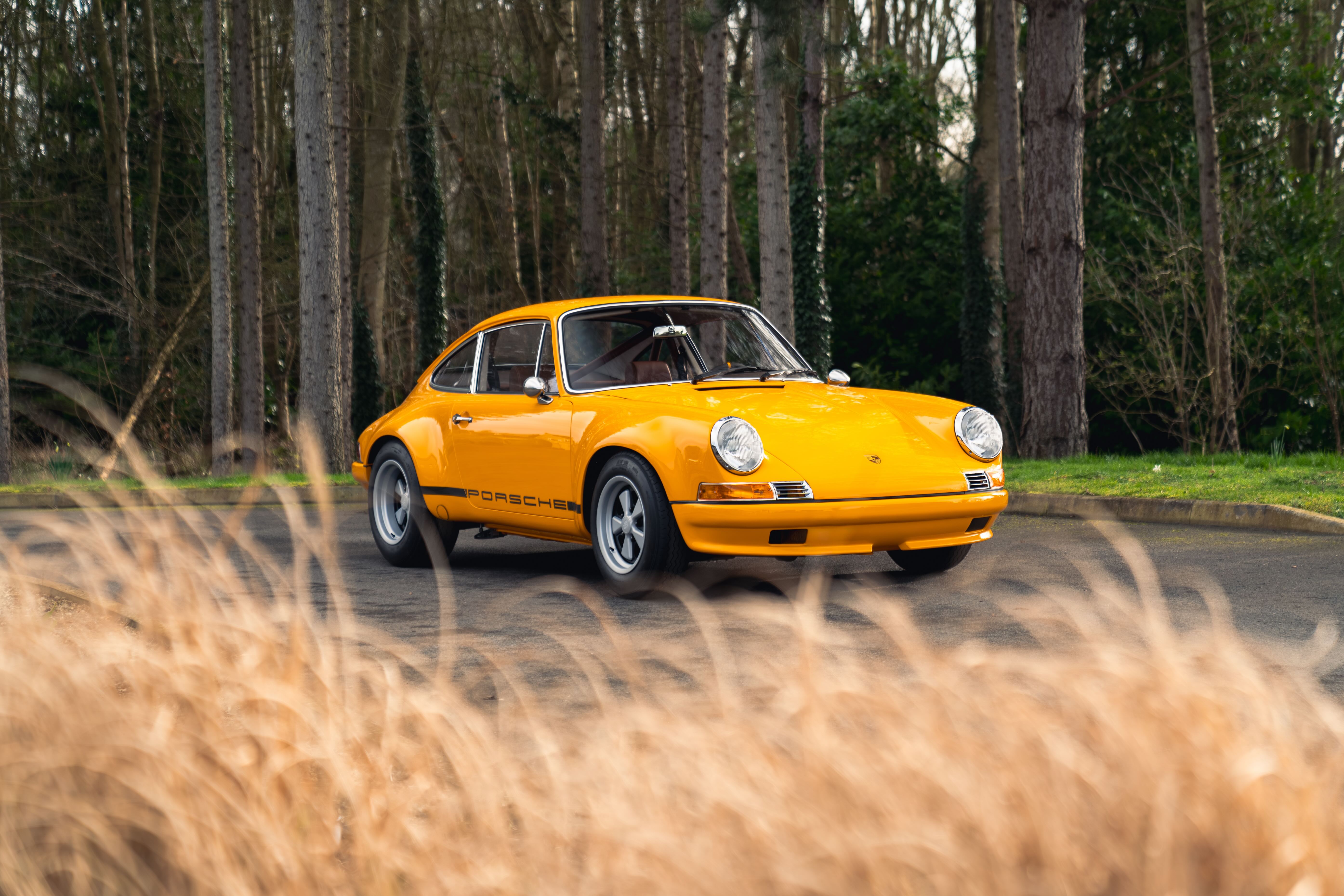 A yellow Tuthill 911K sits in front of some shrubs